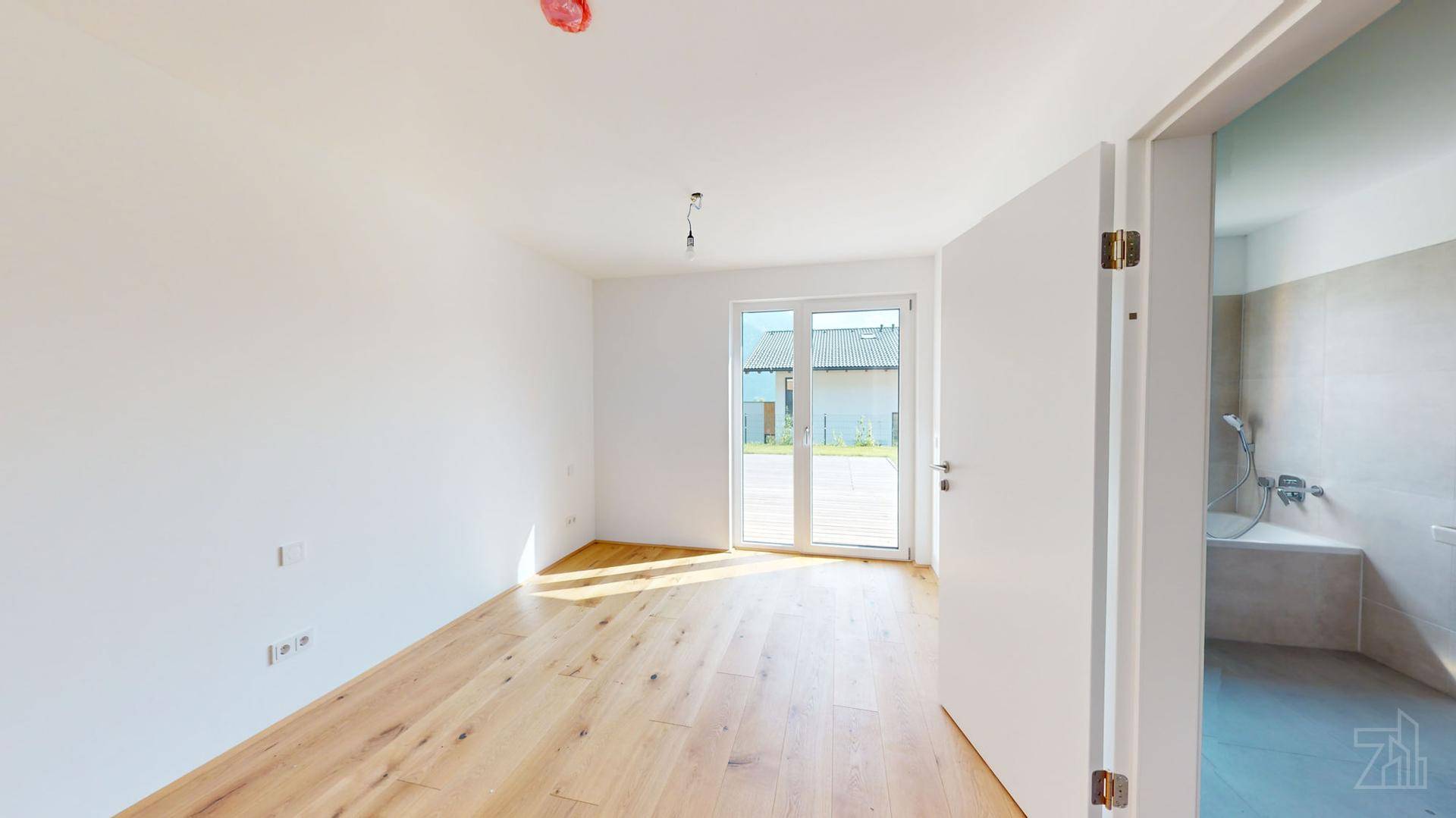 Helles Schlafzimmer mit Holzboden und Blick auf den Garten, angrenzend an ein modernes Badezimmer.