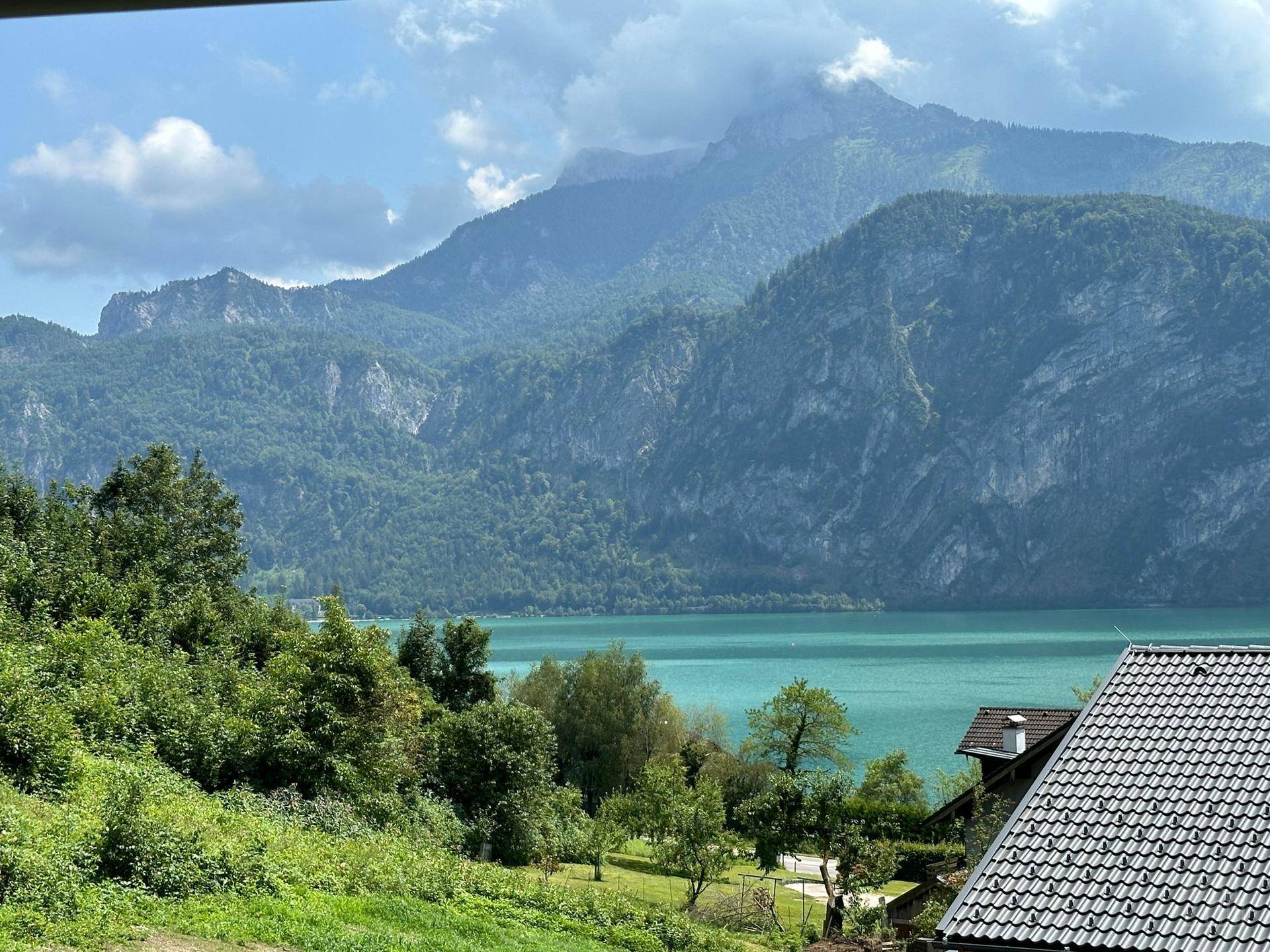Panoramablick auf den See und die majestätischen Berge, umgeben von üppiger grüner Landschaft.