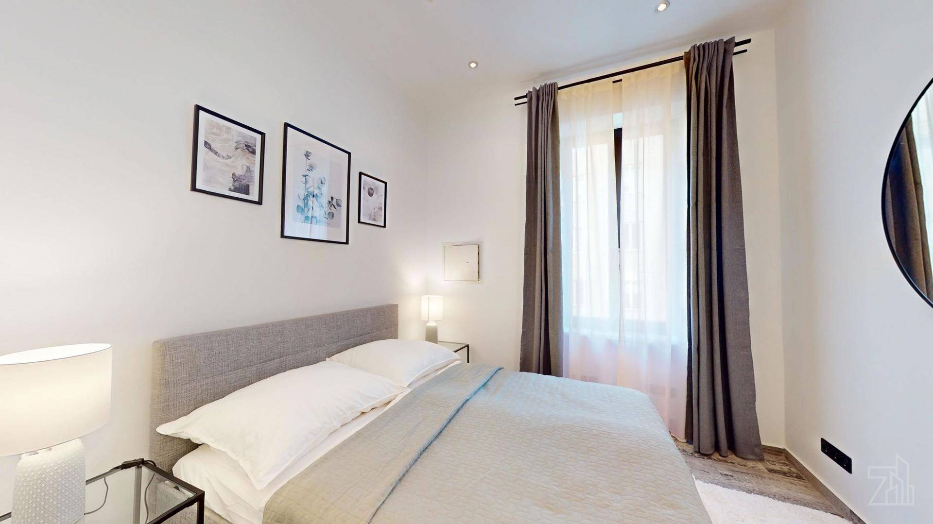 Gemütliches Schlafzimmer mit großem Fenster, grauen Vorhängen und modernem Holzboden.