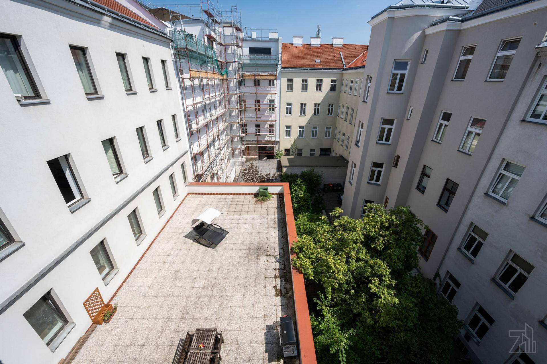 Große Dachterrasse mit Sitzgelegenheiten und Blick auf die umliegenden Gebäude und Bäume.