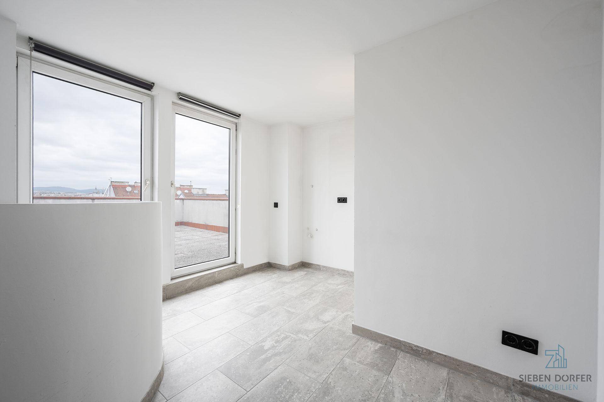 Heller Raum mit Fliesenboden und Zugang zu einer Dachterrasse.