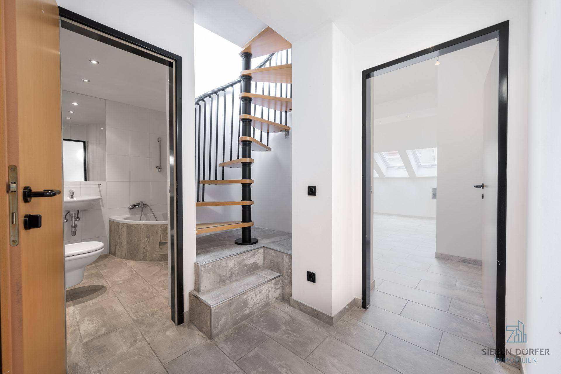 Flur mit Wendeltreppe, Zugang zu Bad und weiterem Raum, Fliesenboden.