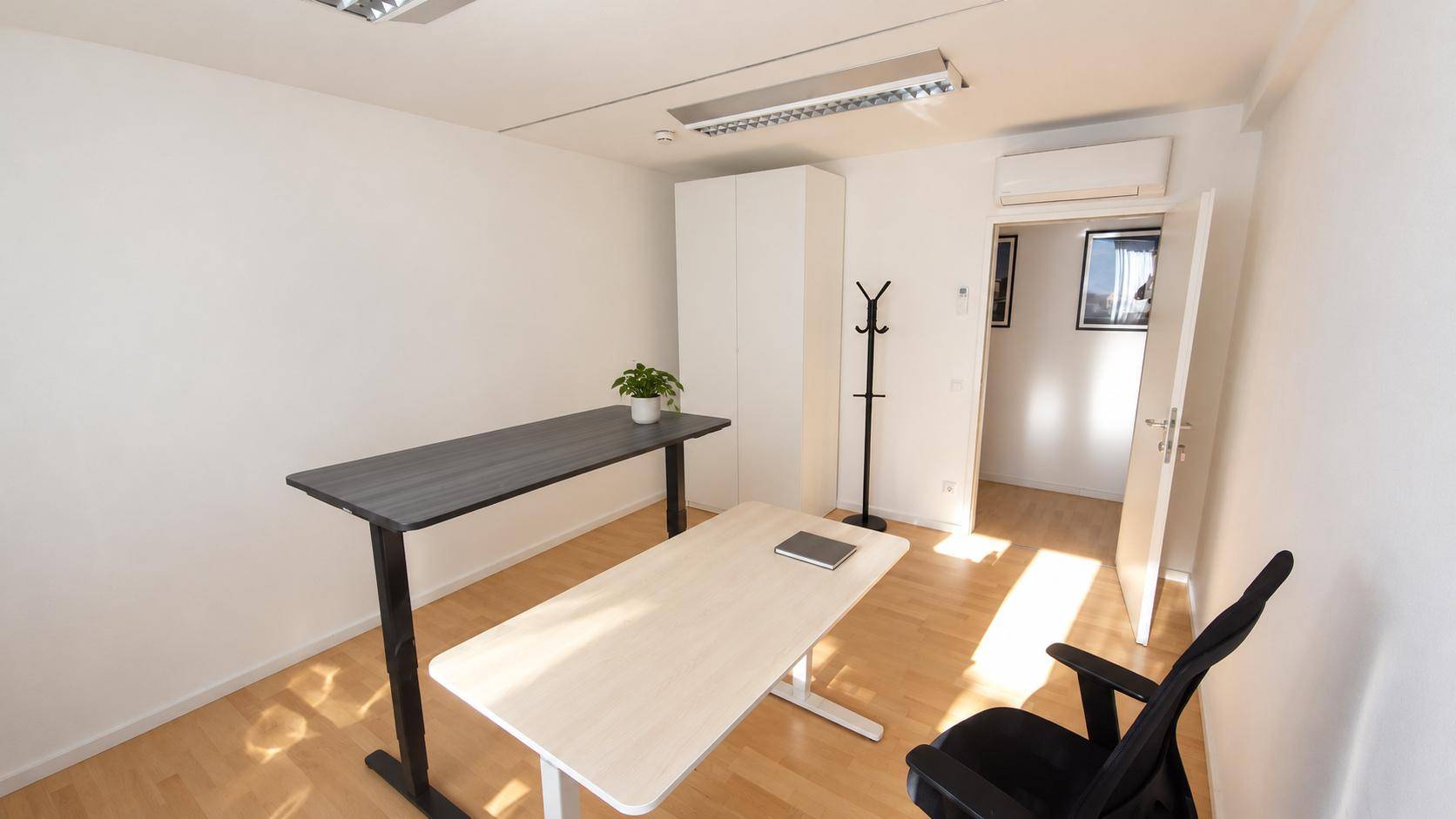 Geräumiges Büro mit Klimaanlage, zwei Schreibtischen und einem Kleiderschrank, ideal für produktives Arbeiten.