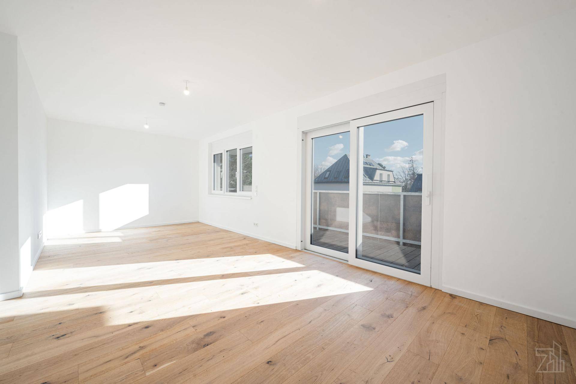 Heller, leerer Wohnraum mit Holzboden und großen Fenstern, bereit zur individuellen Gestaltung.