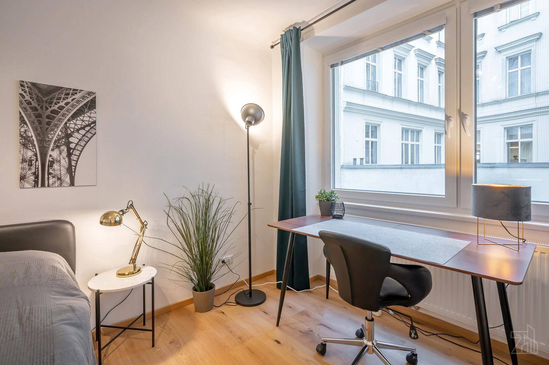 Heller Arbeitsbereich im Schlafzimmer mit Schreibtisch, Stuhl und großem Fenster für Tageslicht.