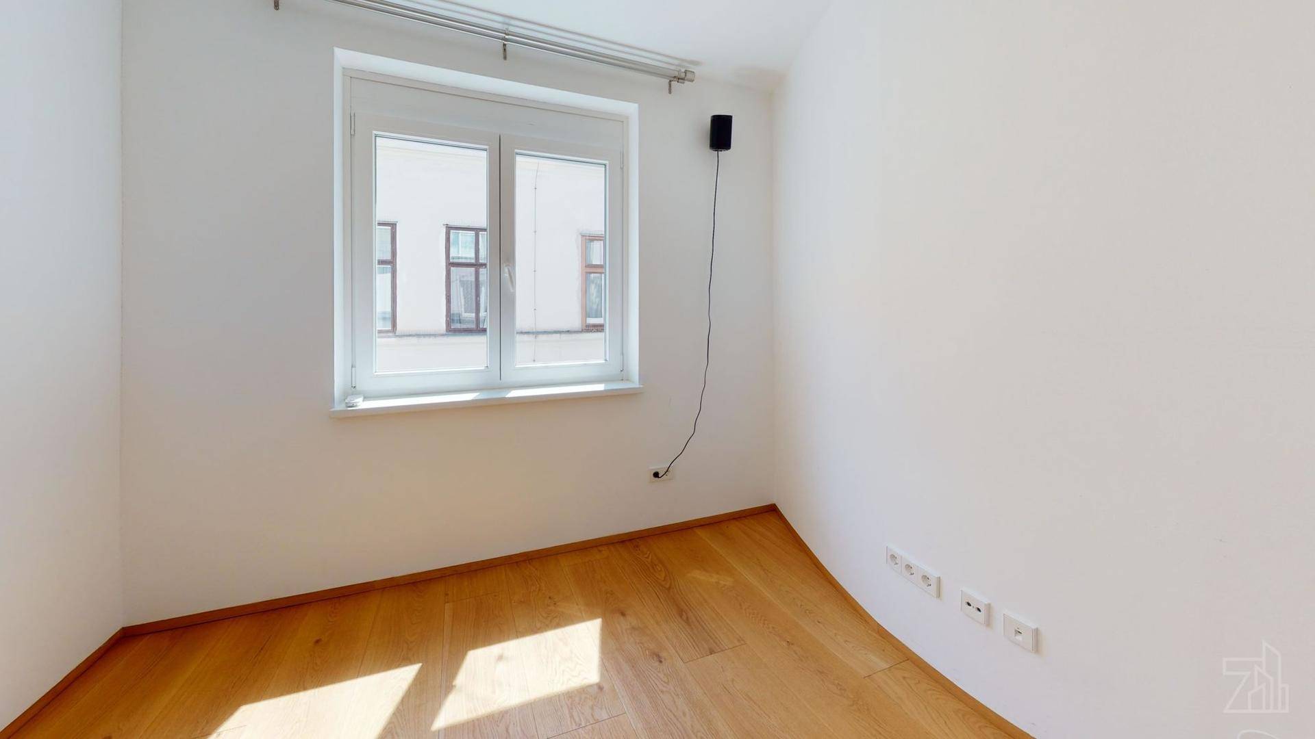 Helles Zimmer mit Holzboden und einem Fenster, bereit zur individuellen Gestaltung.