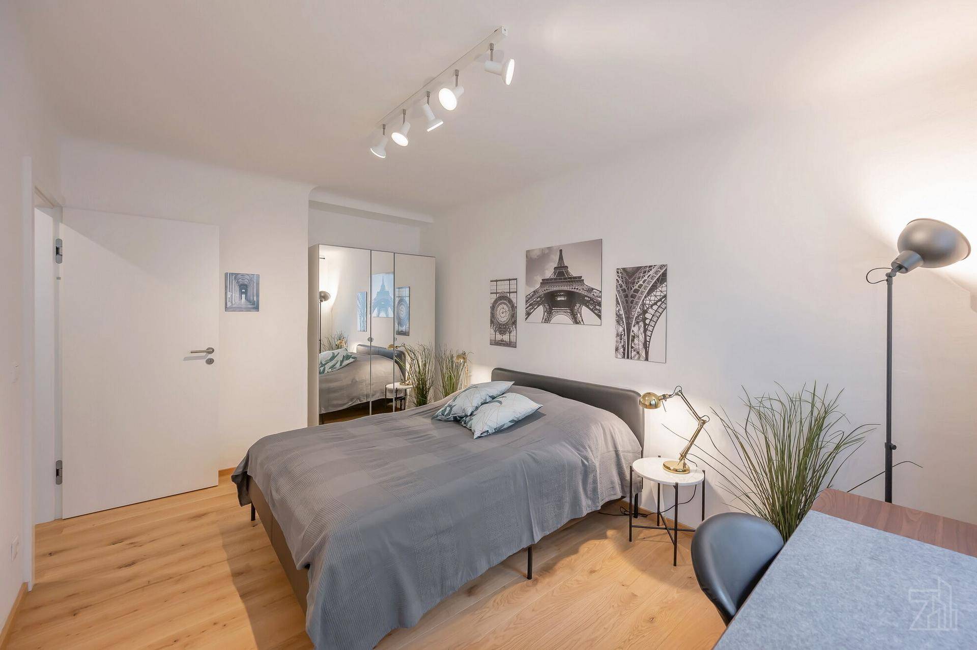 Gemütliches Schlafzimmer mit Doppelbett, Spiegelschrank und Holzboden, hell und modern eingerichtet.