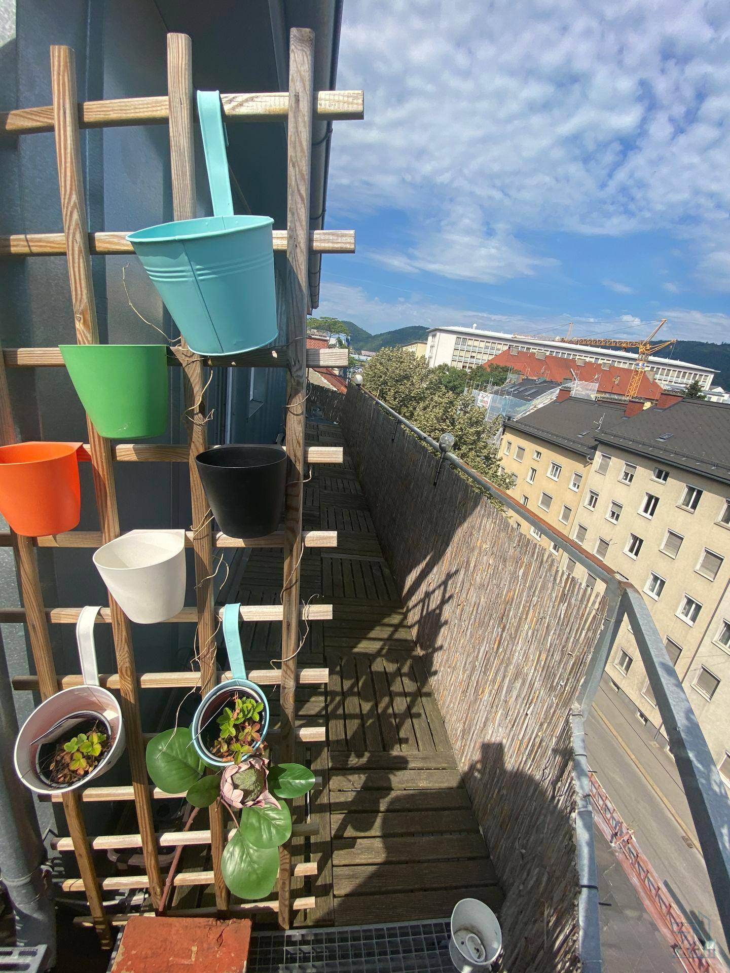 Balkon mit Pflanzen in bunten Töpfen und weitem Blick über die Stadt, ideal zum Entspannen.