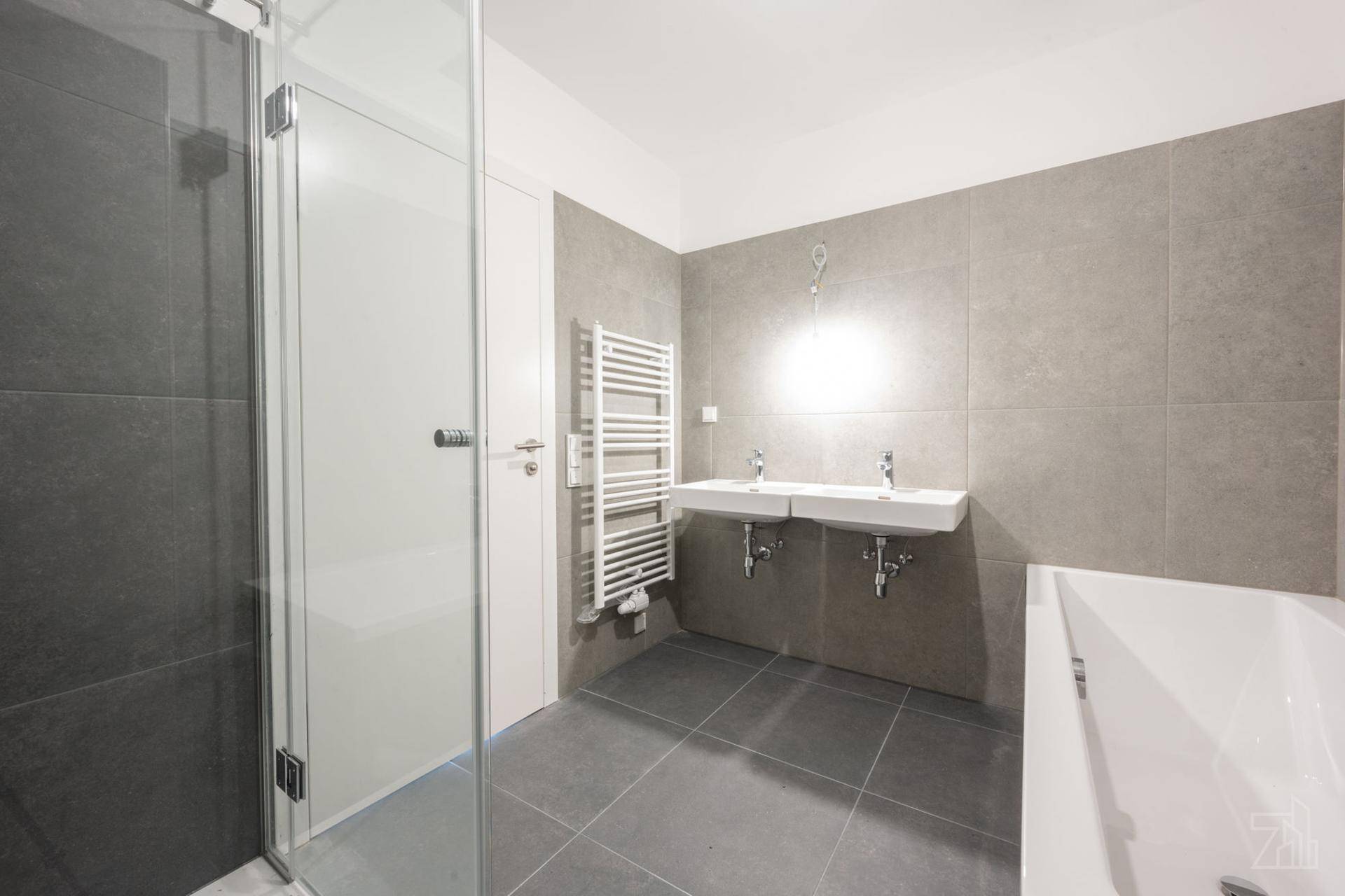 Helles Badezimmer mit Doppelwaschbecken, Dusche, Badewanne und beheiztem Handtuchhalter.
