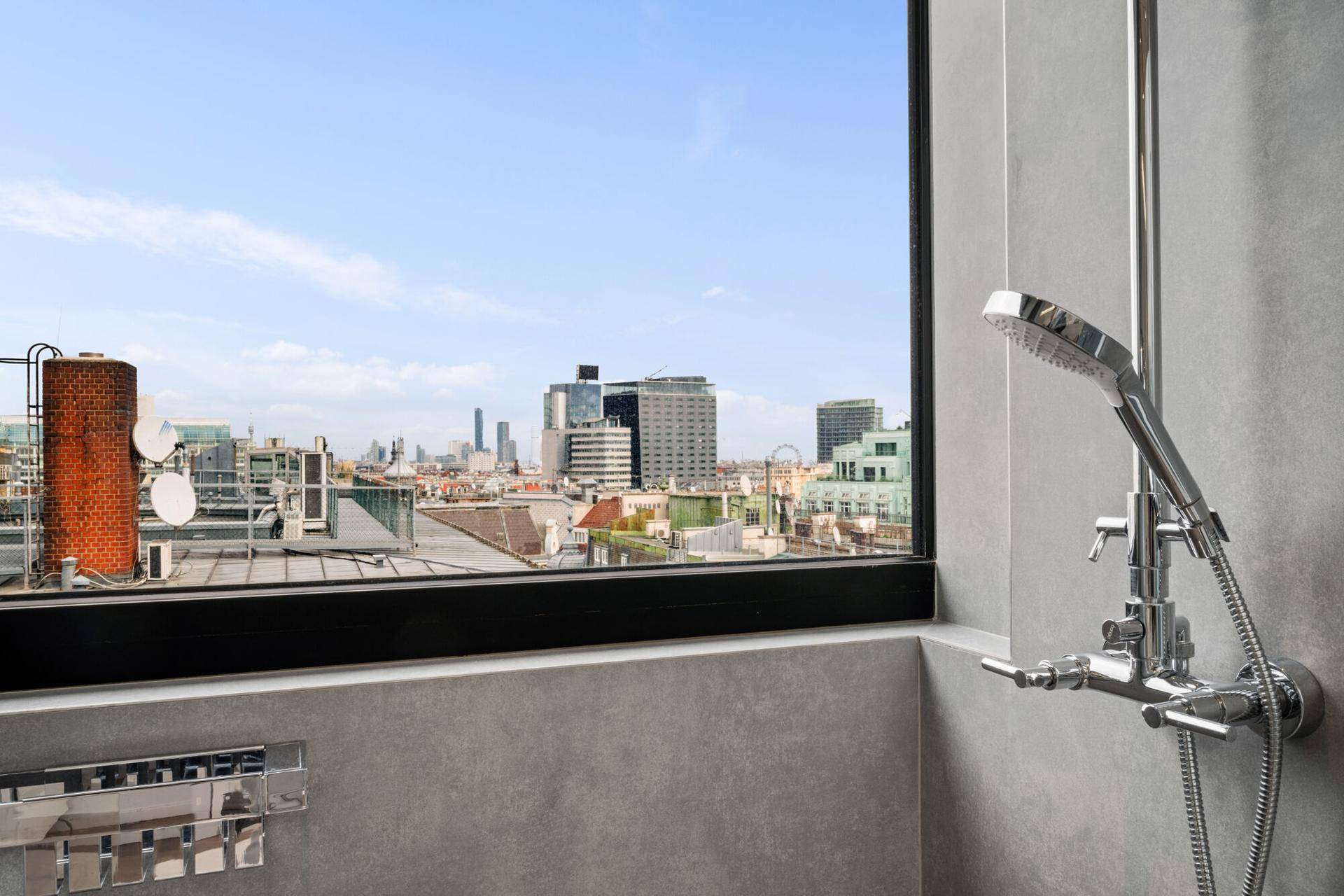 Duschbereich mit großem Fenster, das einen weiten Blick über die Stadt bietet.