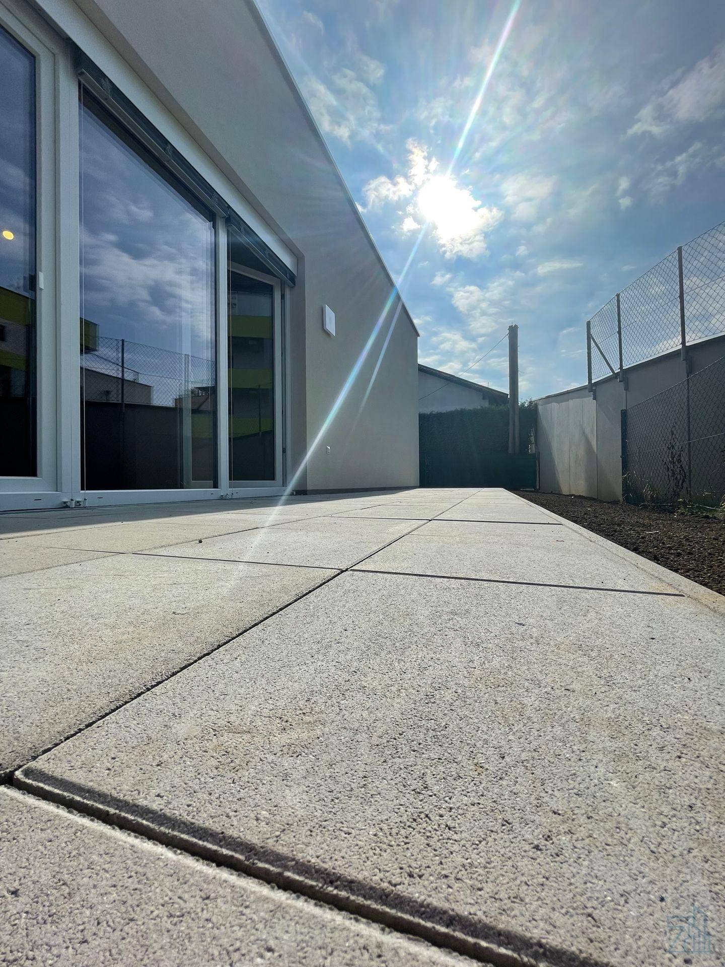 Nahaufnahme der gepflasterten Terrasse mit Sonnenschein und Blick auf den Himmel.