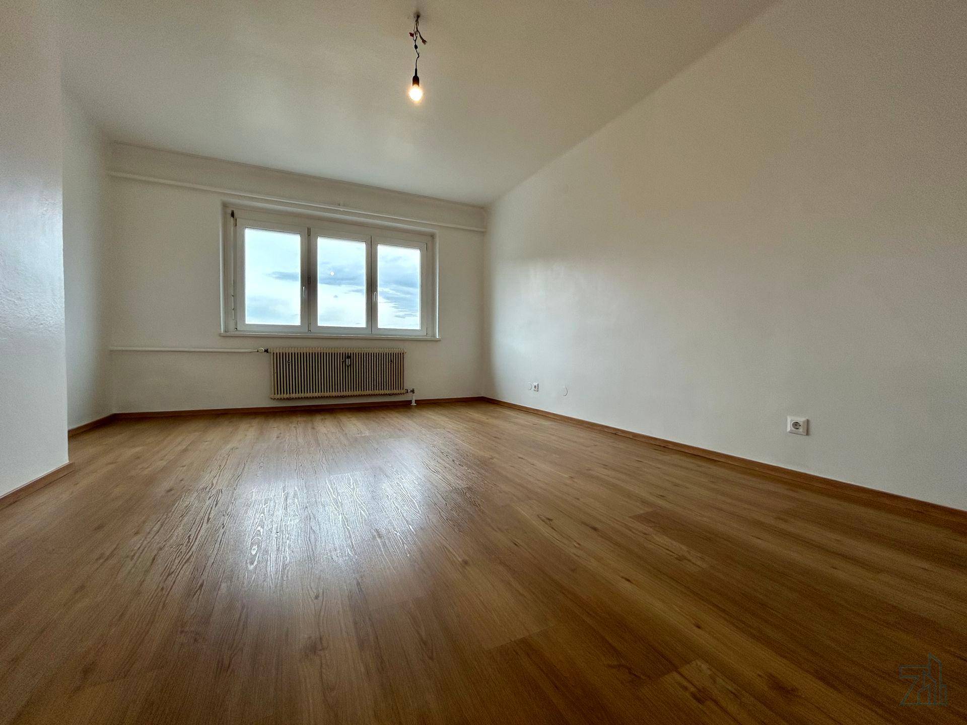 Heller Raum mit Holzfußboden und einem großen Fenster, das einen weiten Blick auf die Landschaft bietet.