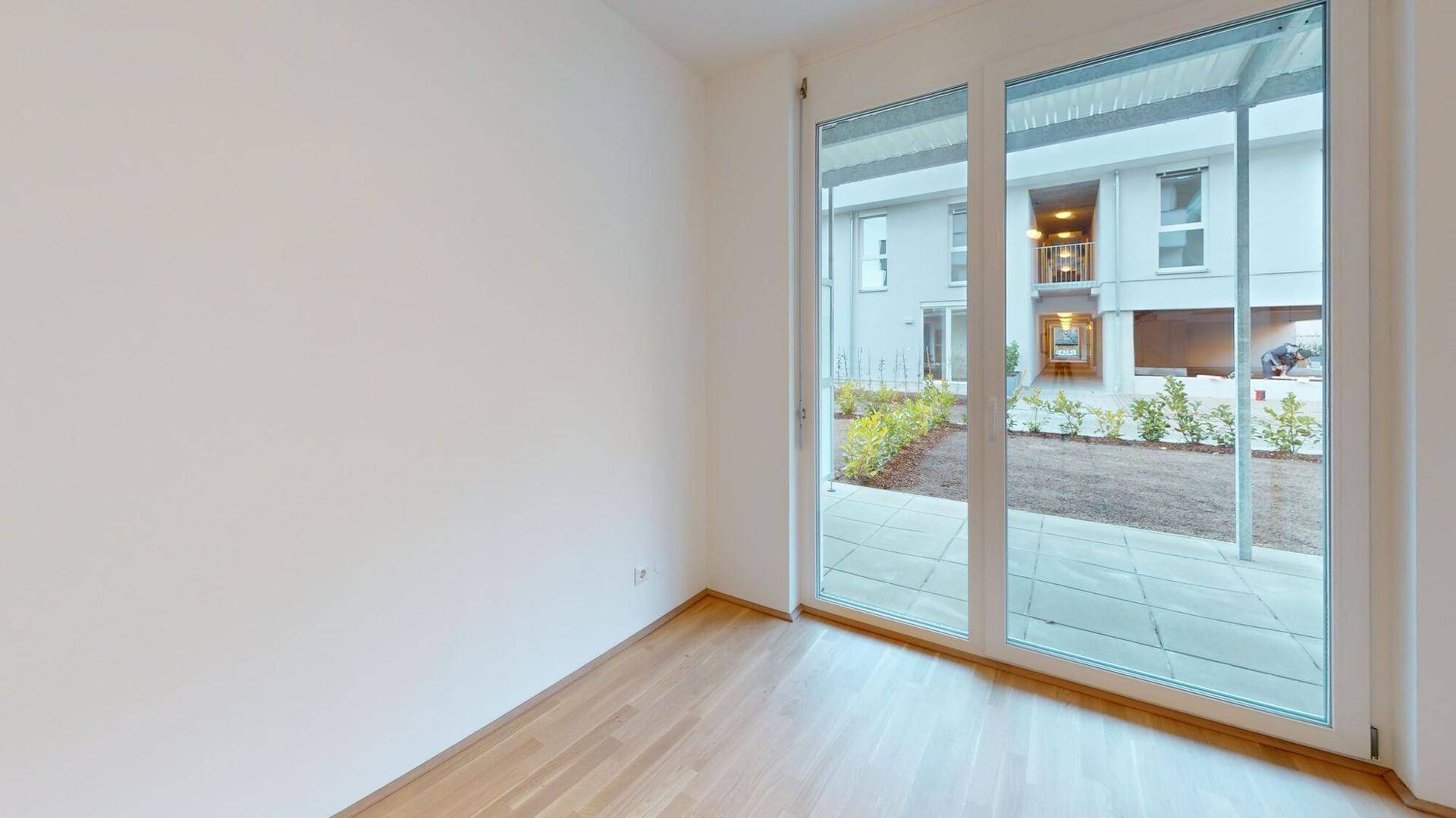Lichtdurchflutetes Zimmer mit Parkettboden und Blick auf den ruhigen Innenhof.