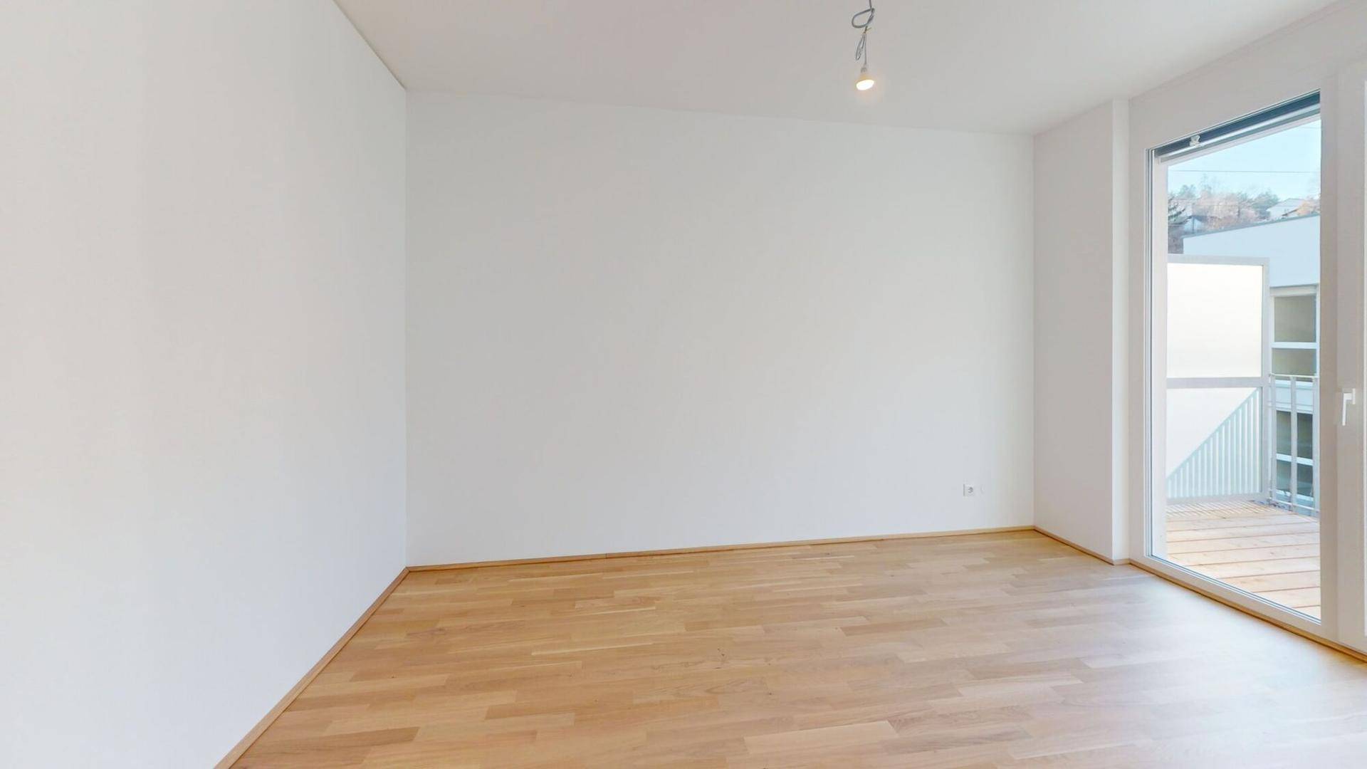 Geräumiger, heller Raum mit Holzboden und großen Fenstern, die viel Tageslicht hereinlassen.