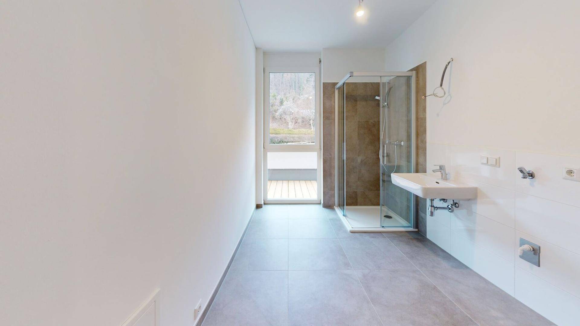 Modernes Badezimmer mit Duschkabine, Einzelwaschbecken und großem Fenster mit Zugang nach draußen.
