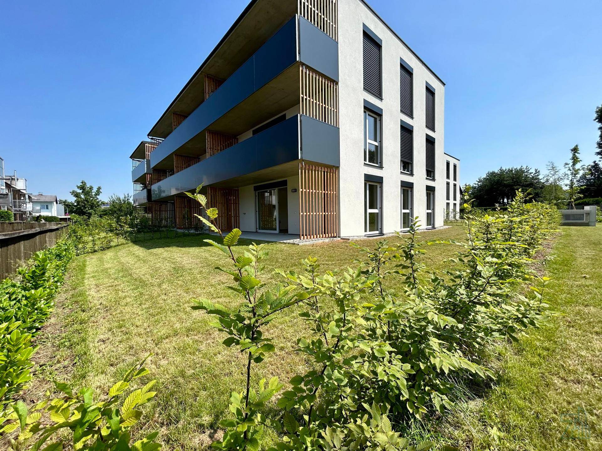 Neubau-Wohngebäude mit moderner Architektur, Balkonen und gepflegter Grünanlage.