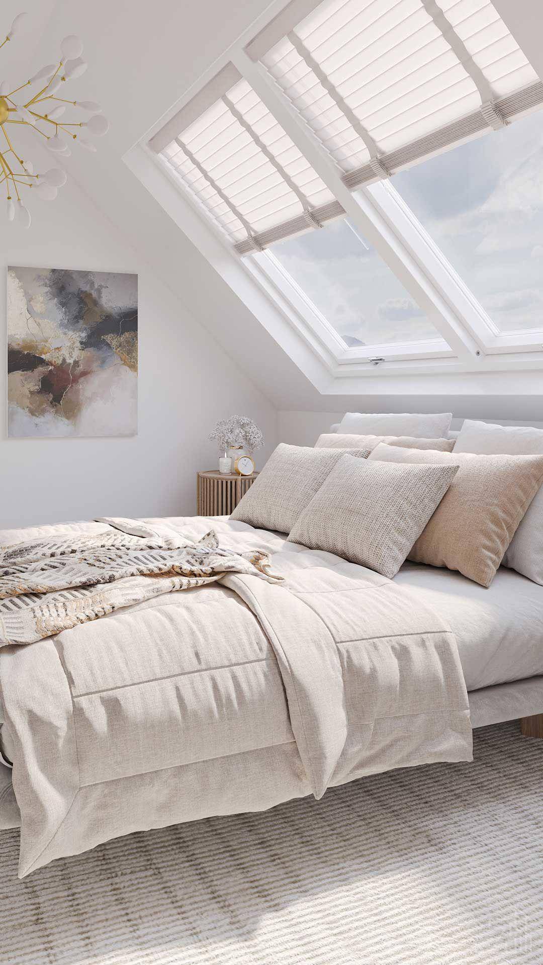 Helles Schlafzimmer im Dachgeschoss mit schrägen Wänden und großen Dachfenstern für viel Tageslicht.
