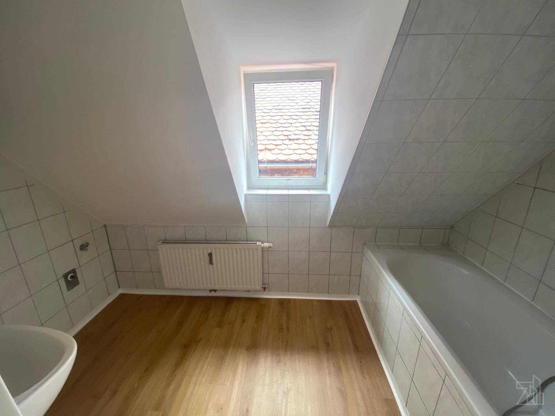 Badezimmer im Dachgeschoss mit Badewanne, Fliesen und Dachfenster.