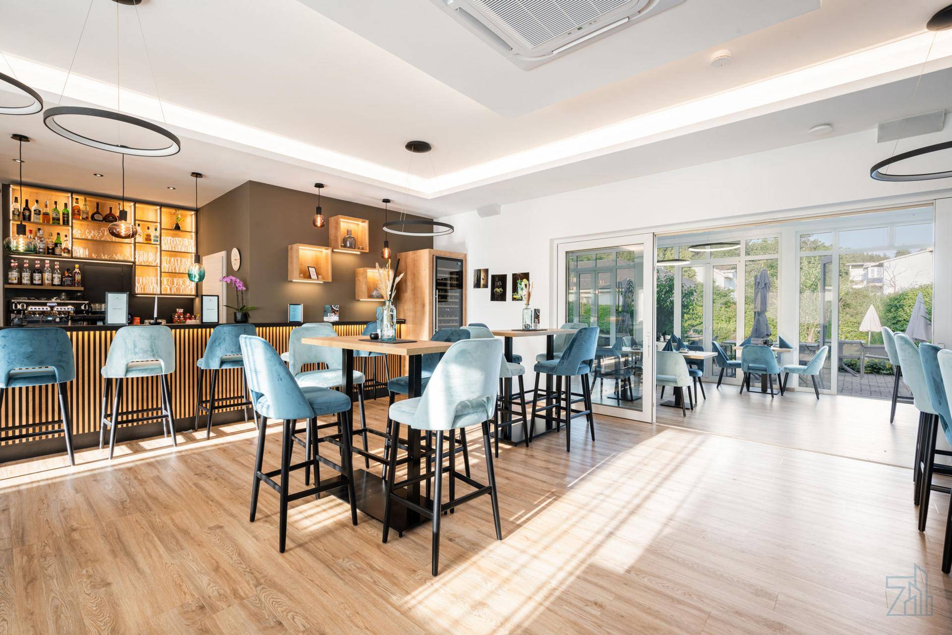 Moderne Bar und Loungebereich mit hohen Tischen, Barhockern und Zugang zur Terrasse.