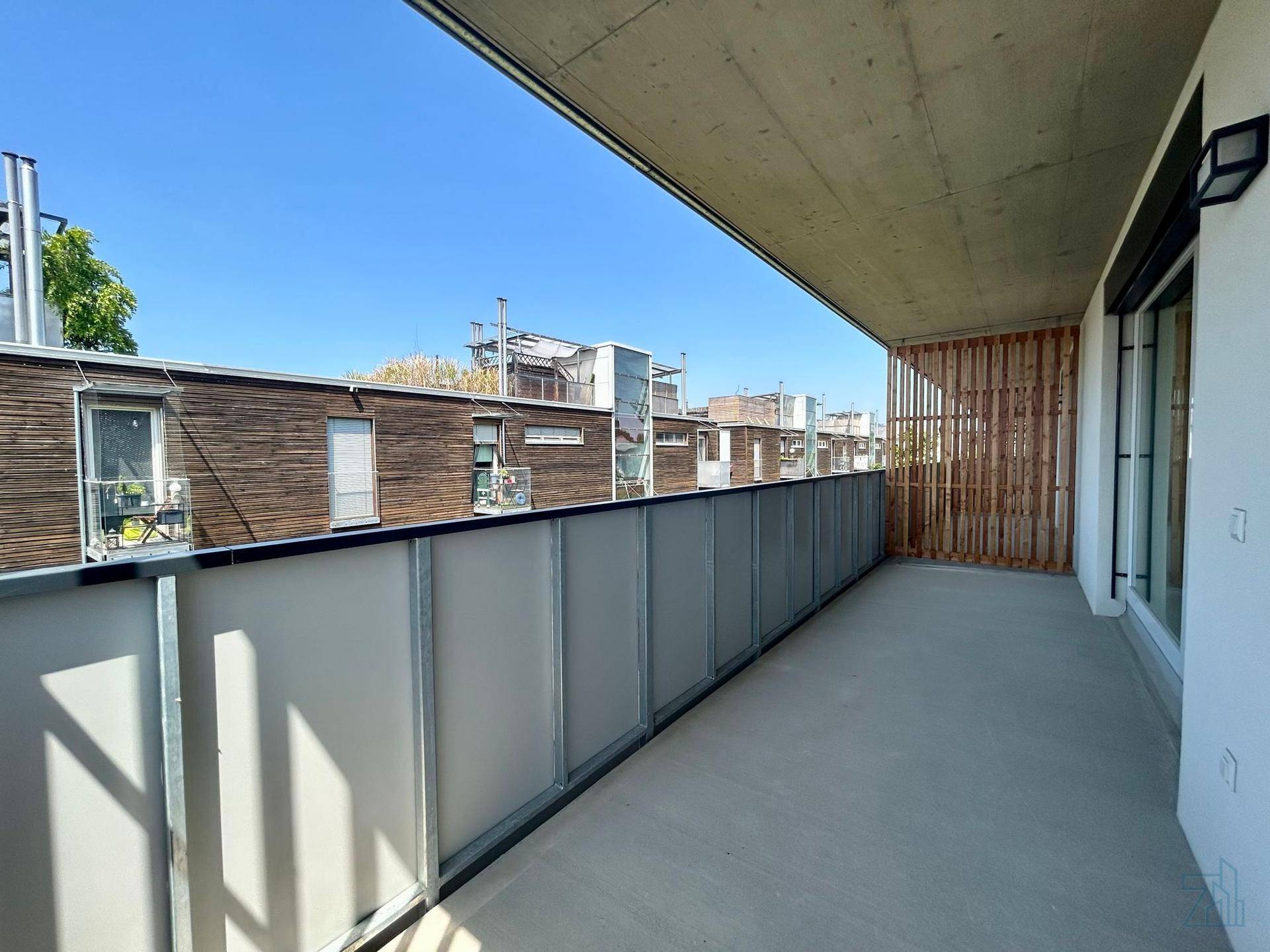 Geräumiger Balkon mit moderner Glasbrüstung und Blick auf die Umgebung.