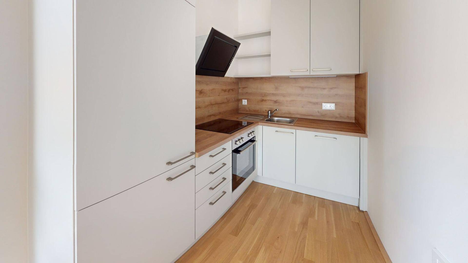 Moderne Einbauküche mit weißen Schränken, Holzoptik-Arbeitsplatte und integrierten Geräten.