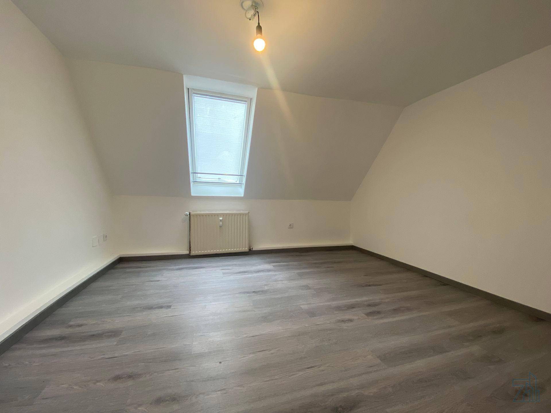 Helles Schlafzimmer im Dachgeschoss mit Dachschräge und einem Dachfenster für natürliches Licht.
