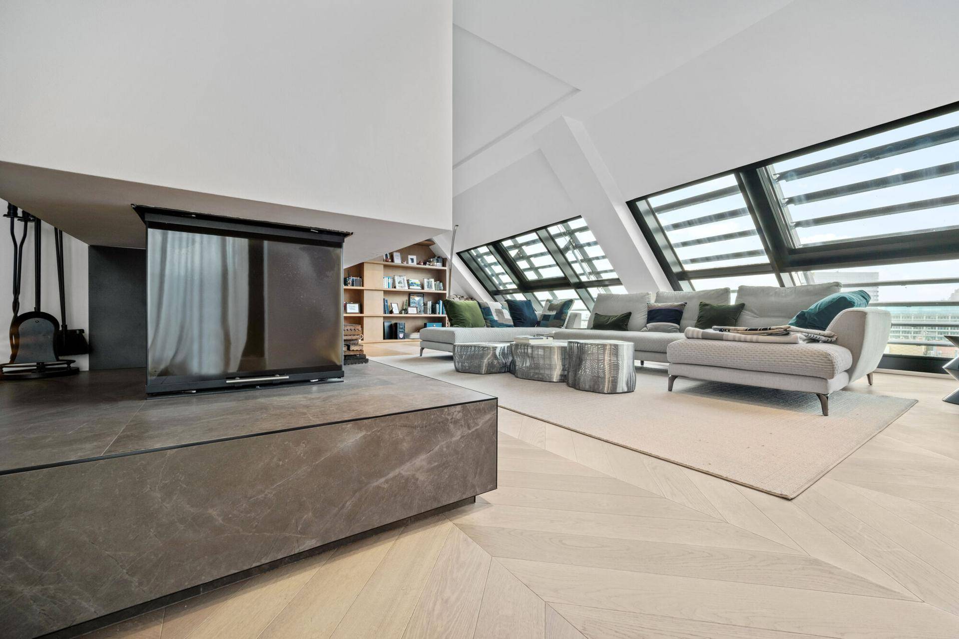 Geräumiges Wohnzimmer mit modernem Kamin, bequemer Couch und schrägen Dachfenstern.