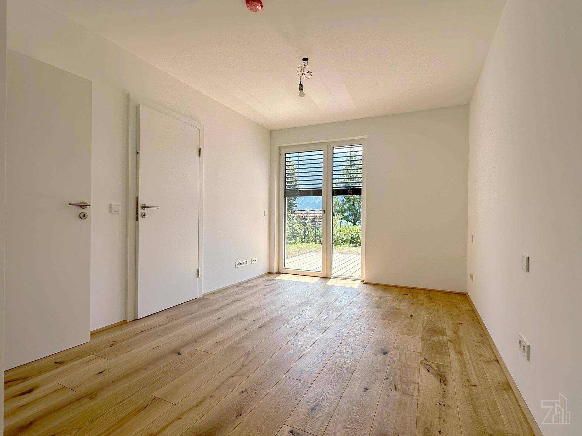 Helles Schlafzimmer mit Holzboden und Zugang zu einem Außenbereich, ideal für frische Luft.
