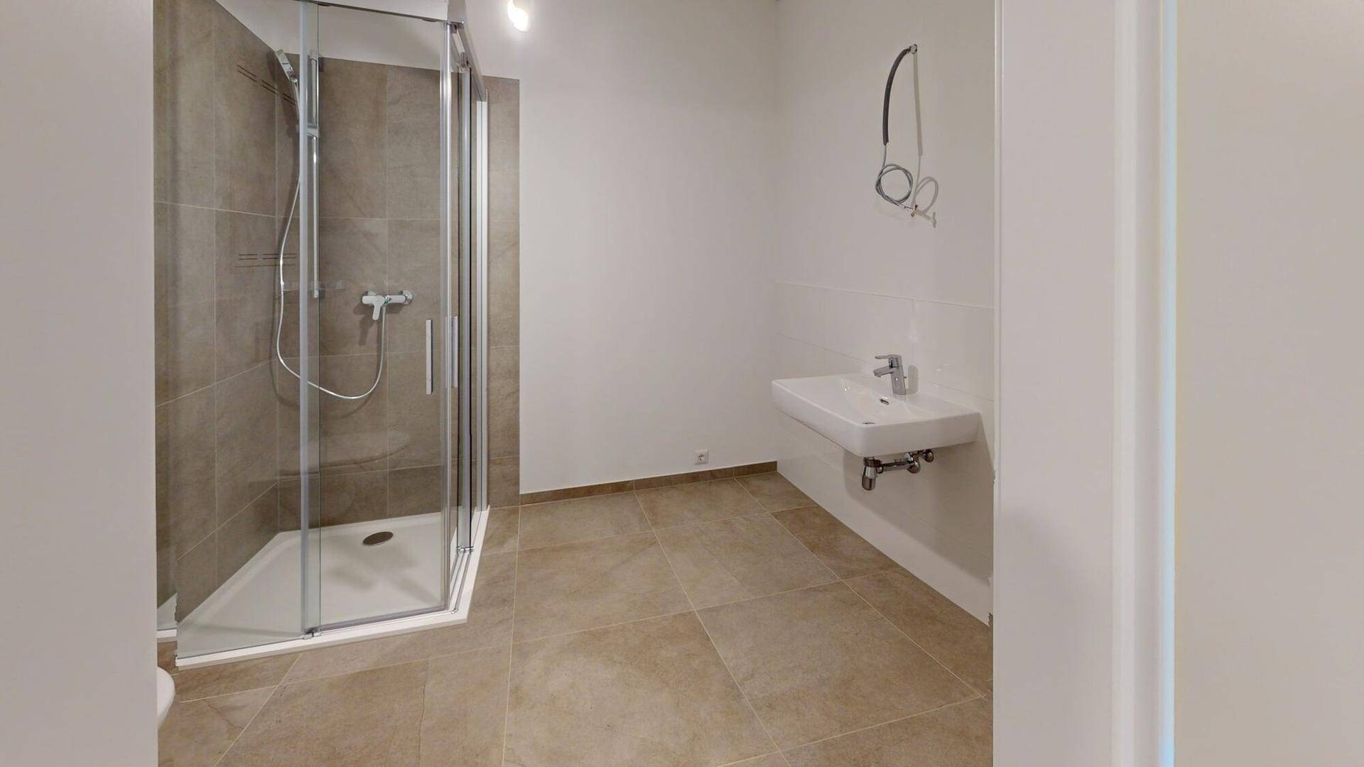 Modernes Badezimmer mit begehbarer Dusche, Wandwaschbecken und großformatigen Fliesen.