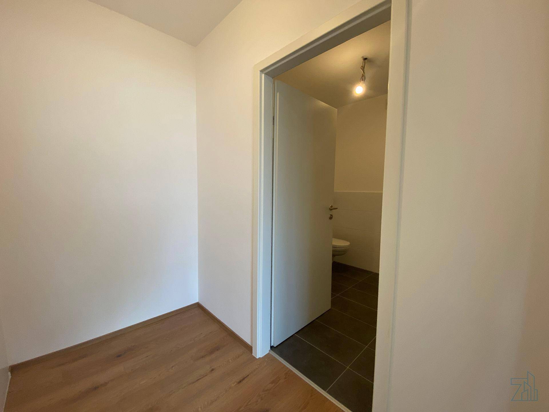 Kleines Gäste-WC mit dunklen Bodenfliesen und einer modernen Toilette.