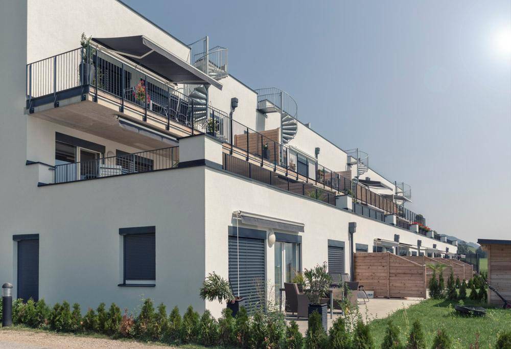 Moderne Wohnanlage mit Balkonen, Außentreppen und ebenerdigen Terrassenbereichen.