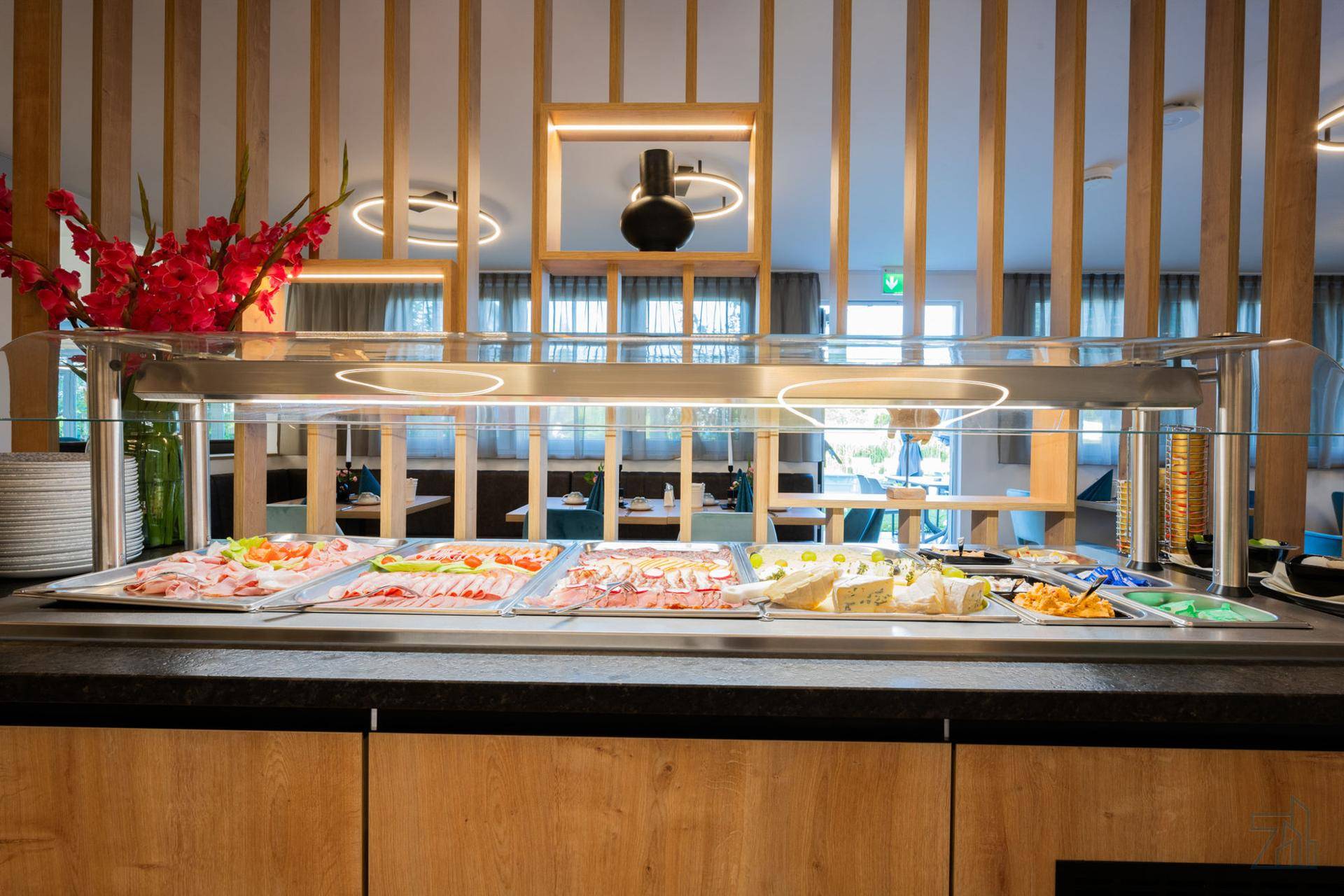 Reichhaltiges Frühstücksbuffet mit Wurst, Käse und frischen Salaten in modernem Ambiente.