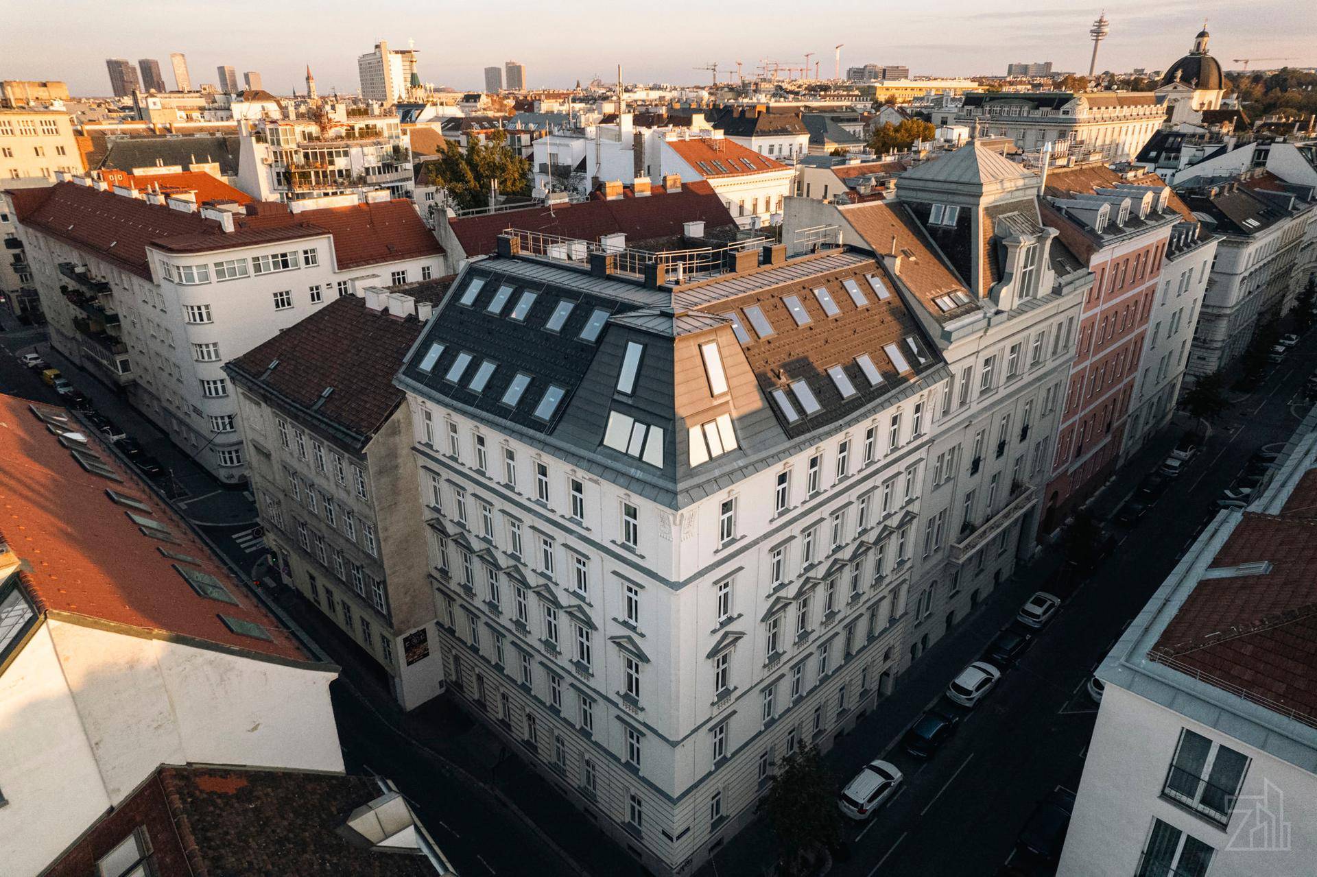 Luftaufnahme eines historischen Stadtgebäudes mit Mansarddach und umliegender Stadtlandschaft.