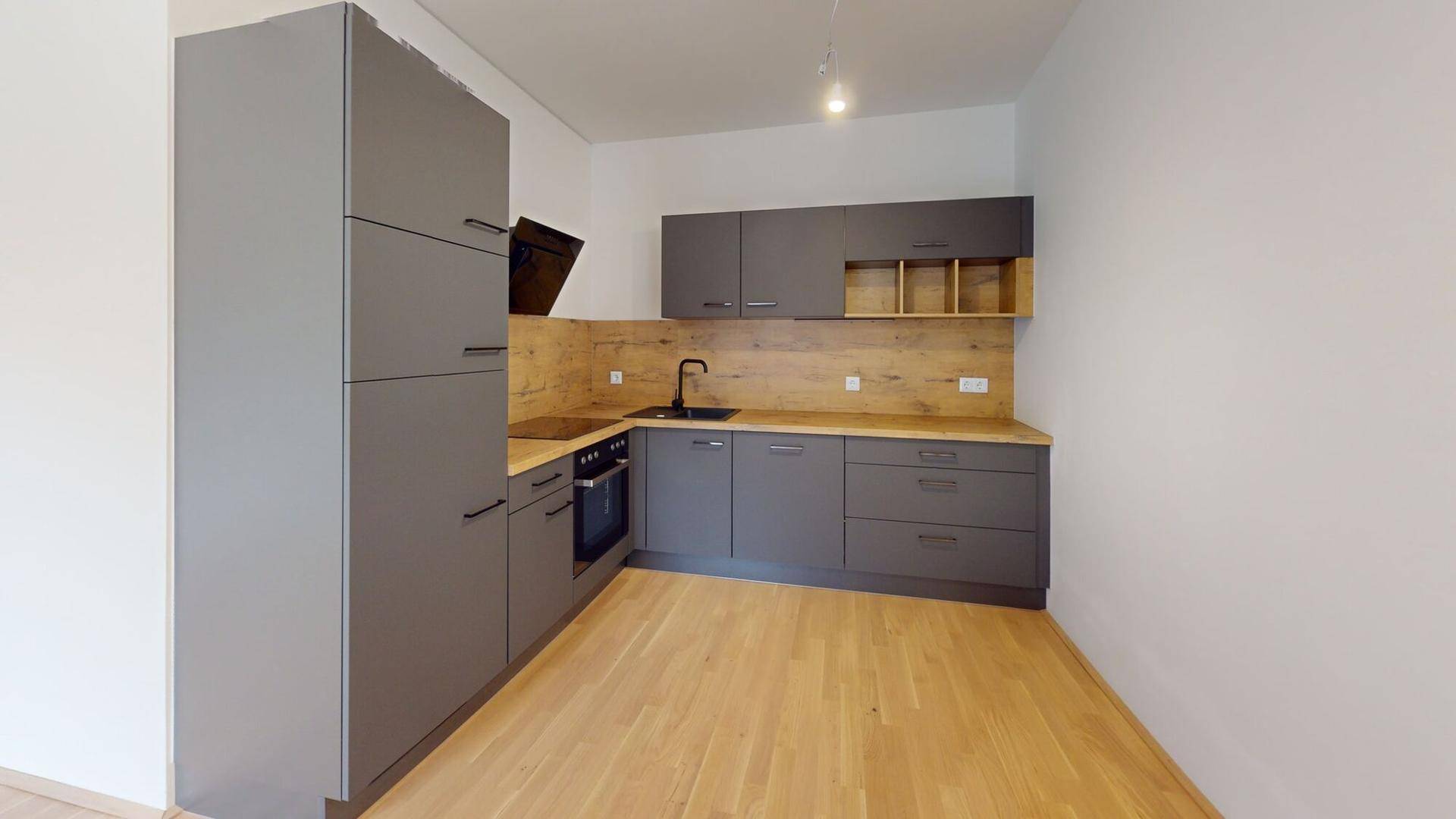 Moderne Einbauküche mit grauen Schränken, Holzakzenten und integrierten Geräten.
