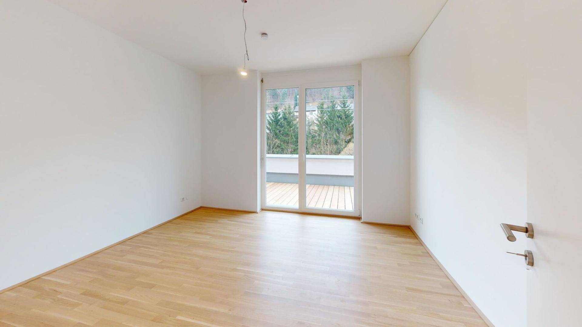 Helles Schlafzimmer mit Parkettboden und direktem Zugang zu einem privaten Außenbereich.