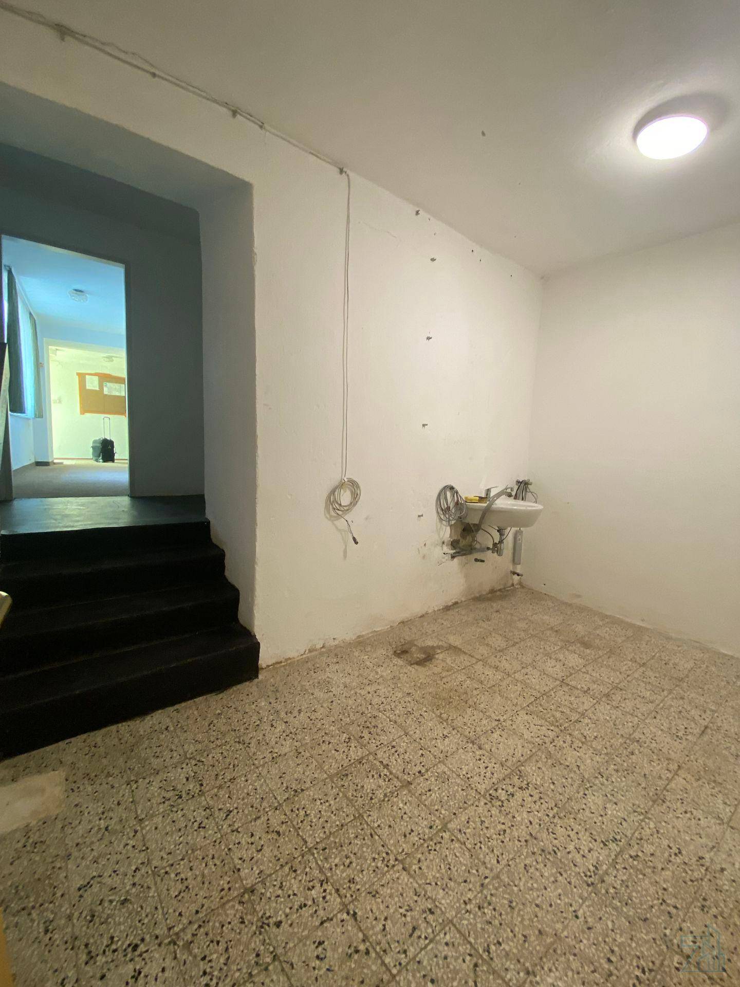 Hauswirtschaftsraum mit Waschbecken und Treppenaufgang, ausgestattet mit Fliesenboden.