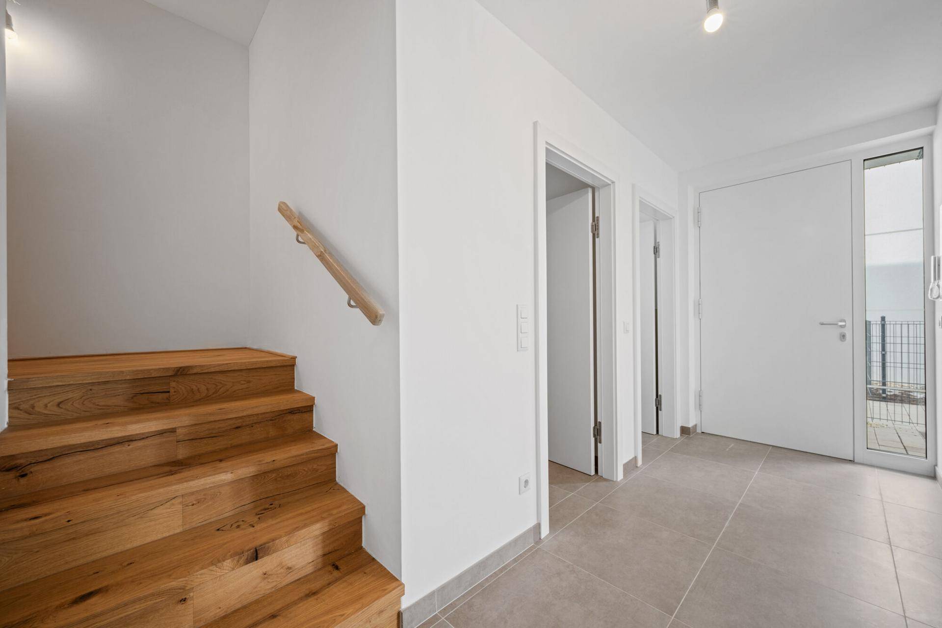Eingangsbereich mit Holztreppe und Fliesenboden, führt zu den oberen Etagen.
