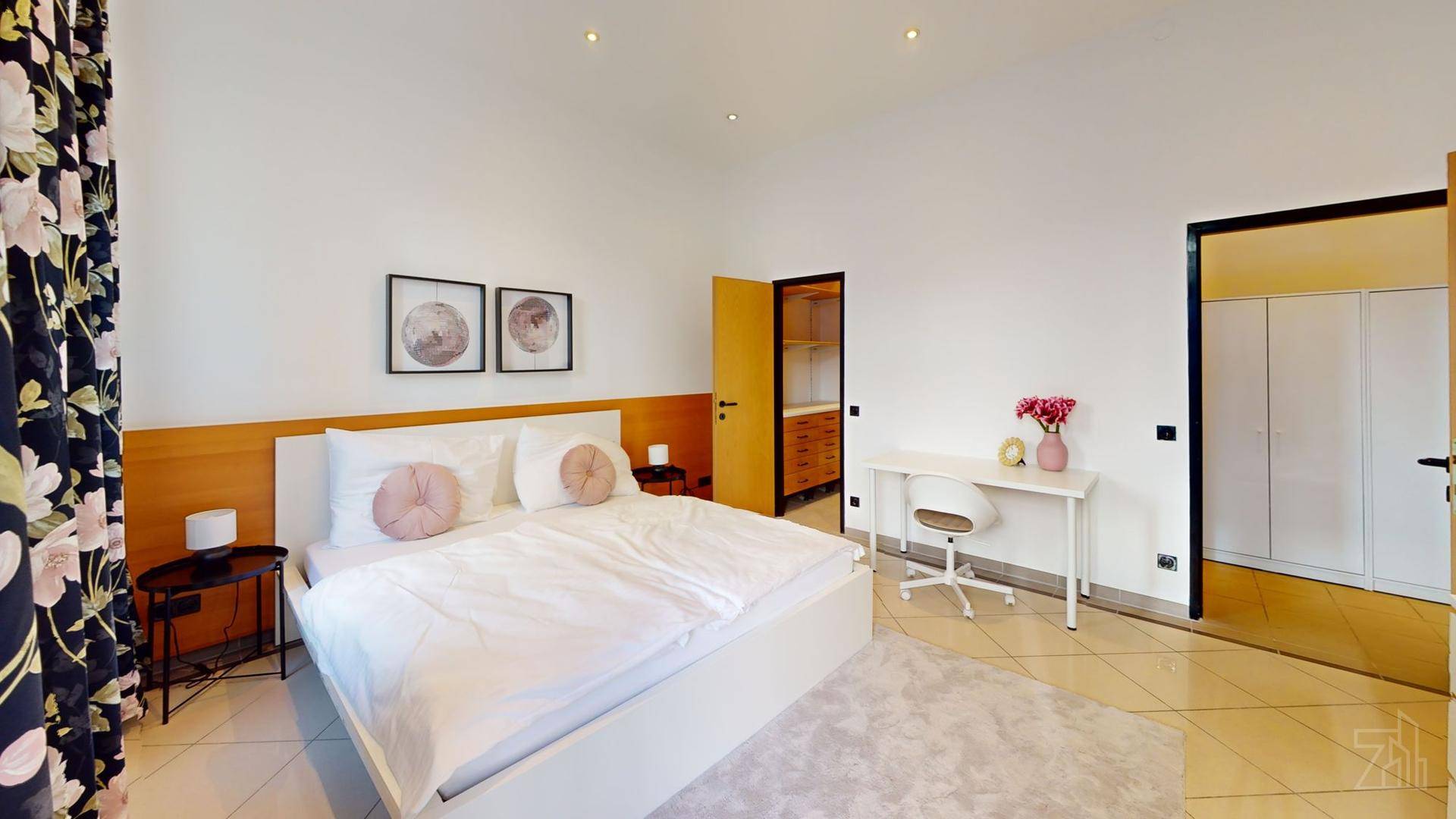 Helles Schlafzimmer mit großem Doppelbett, Schreibtisch und Zugang zu einem begehbaren Kleiderschrank.