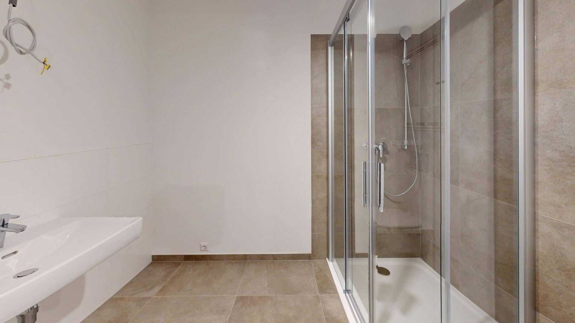 Modernes Badezimmer mit begehbarer Dusche, Waschbecken und hellbraunen Fliesen.