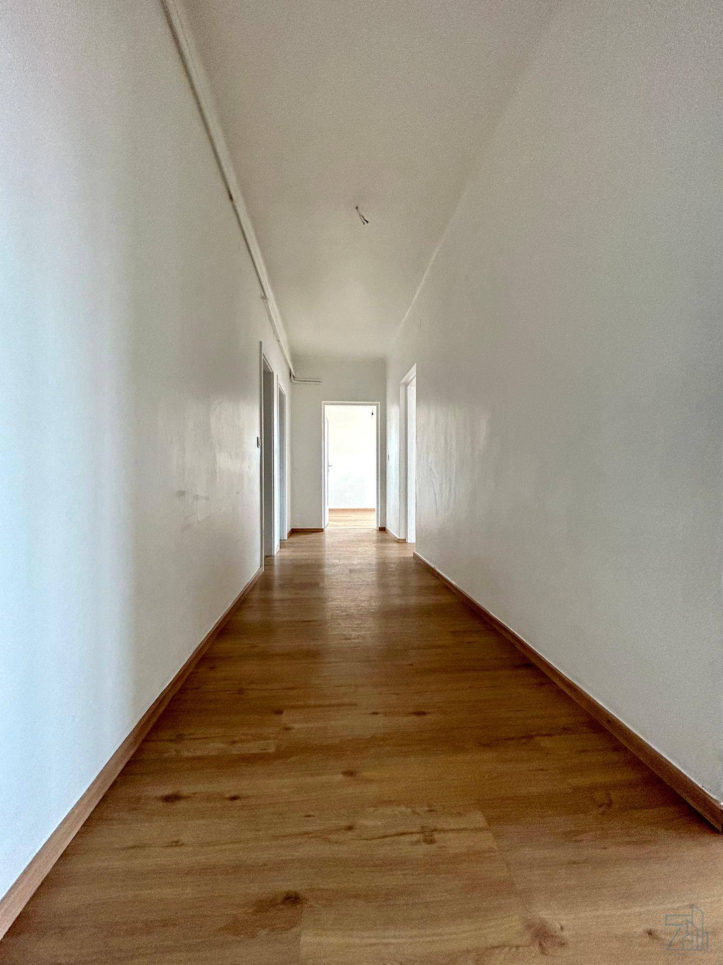 Langer, heller Flur mit Holzboden, der zu verschiedenen Räumen der Wohnung führt.