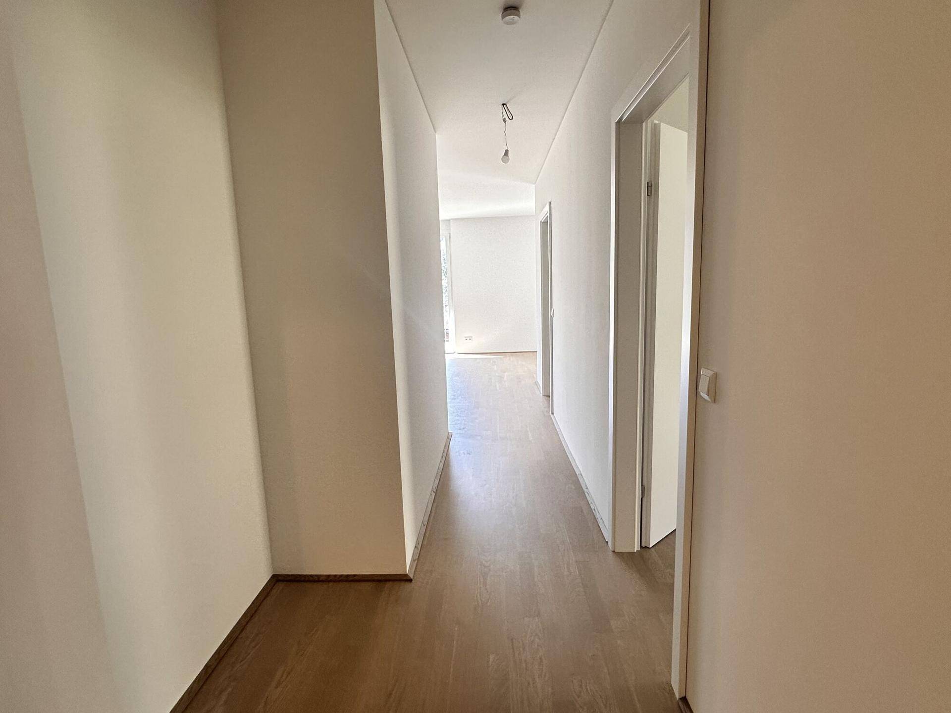 Langer Flur mit Holzboden, der in den offenen Wohnbereich führt.