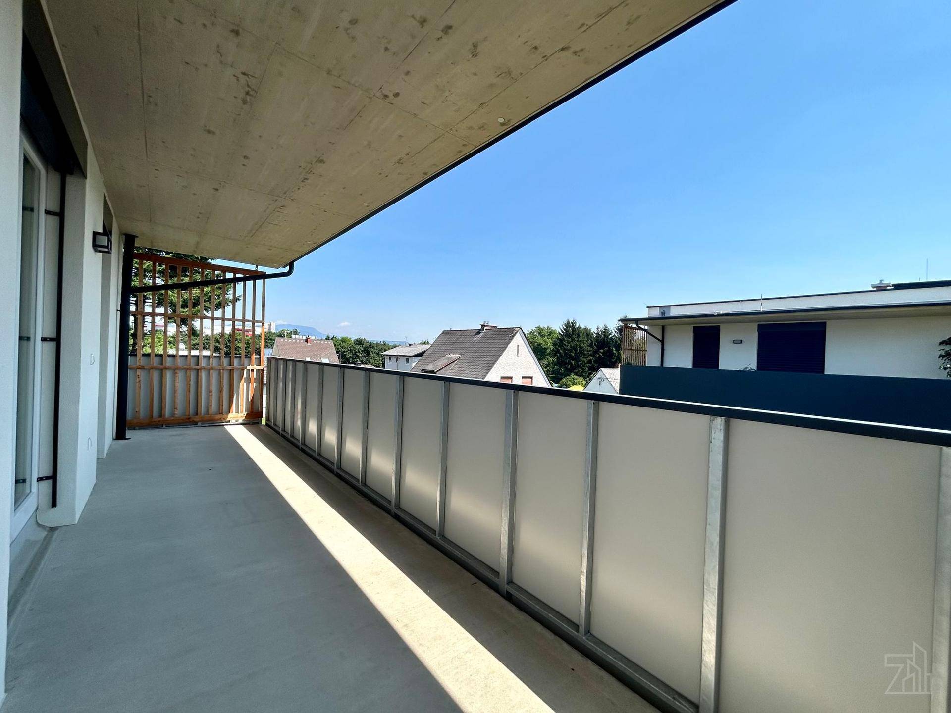 Heller Balkon mit Milchglasbrüstung und weitem Blick über die umliegende Bebauung.