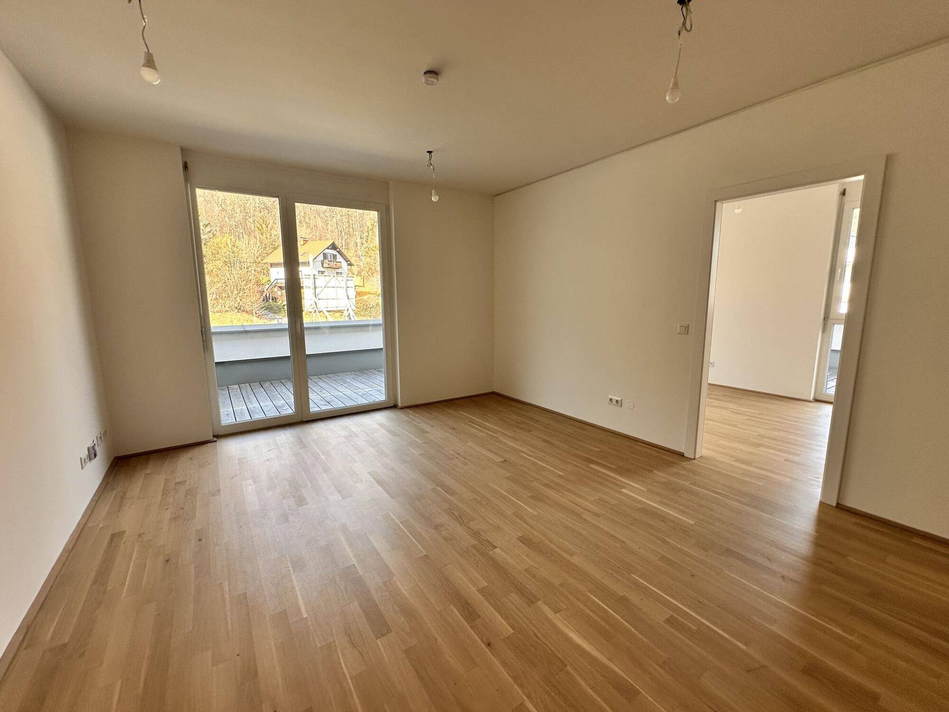 Helles Wohnzimmer mit Eichenparkett und Zugang zu einer großzügigen Dachterrasse.