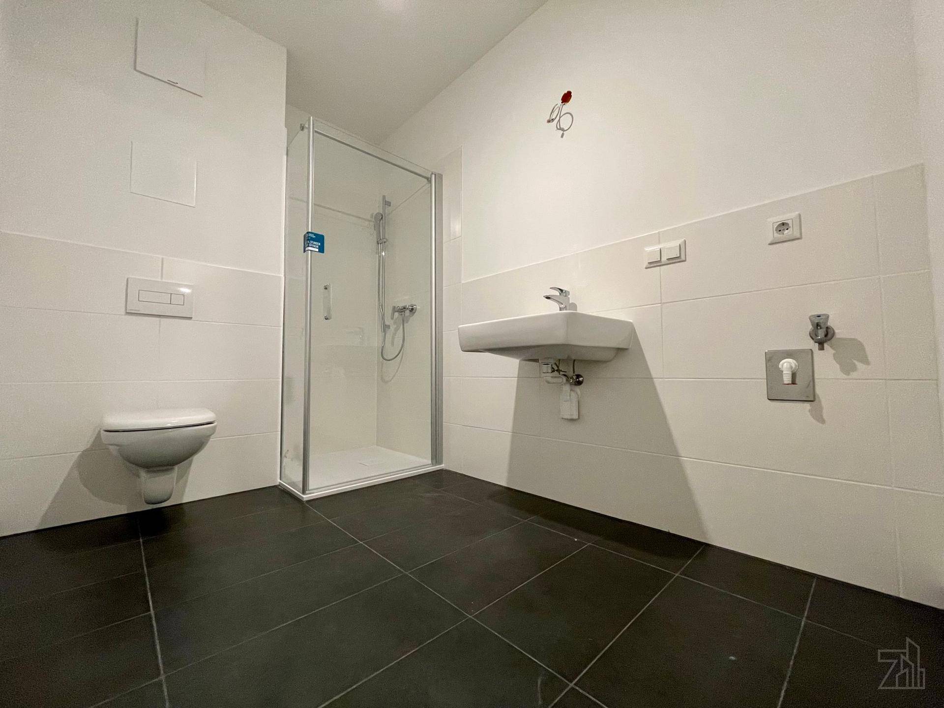 Helles Badezimmer mit Duschkabine, wandhängendem WC und modernem Waschbecken.
