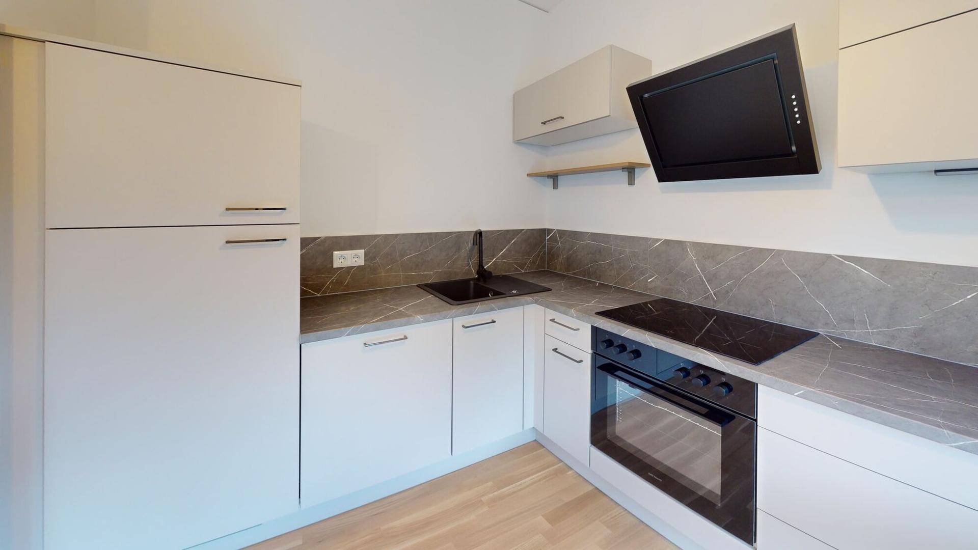 Moderne Einbauküche mit hellgrauen Fronten, dunkler Arbeitsplatte und Induktionskochfeld.