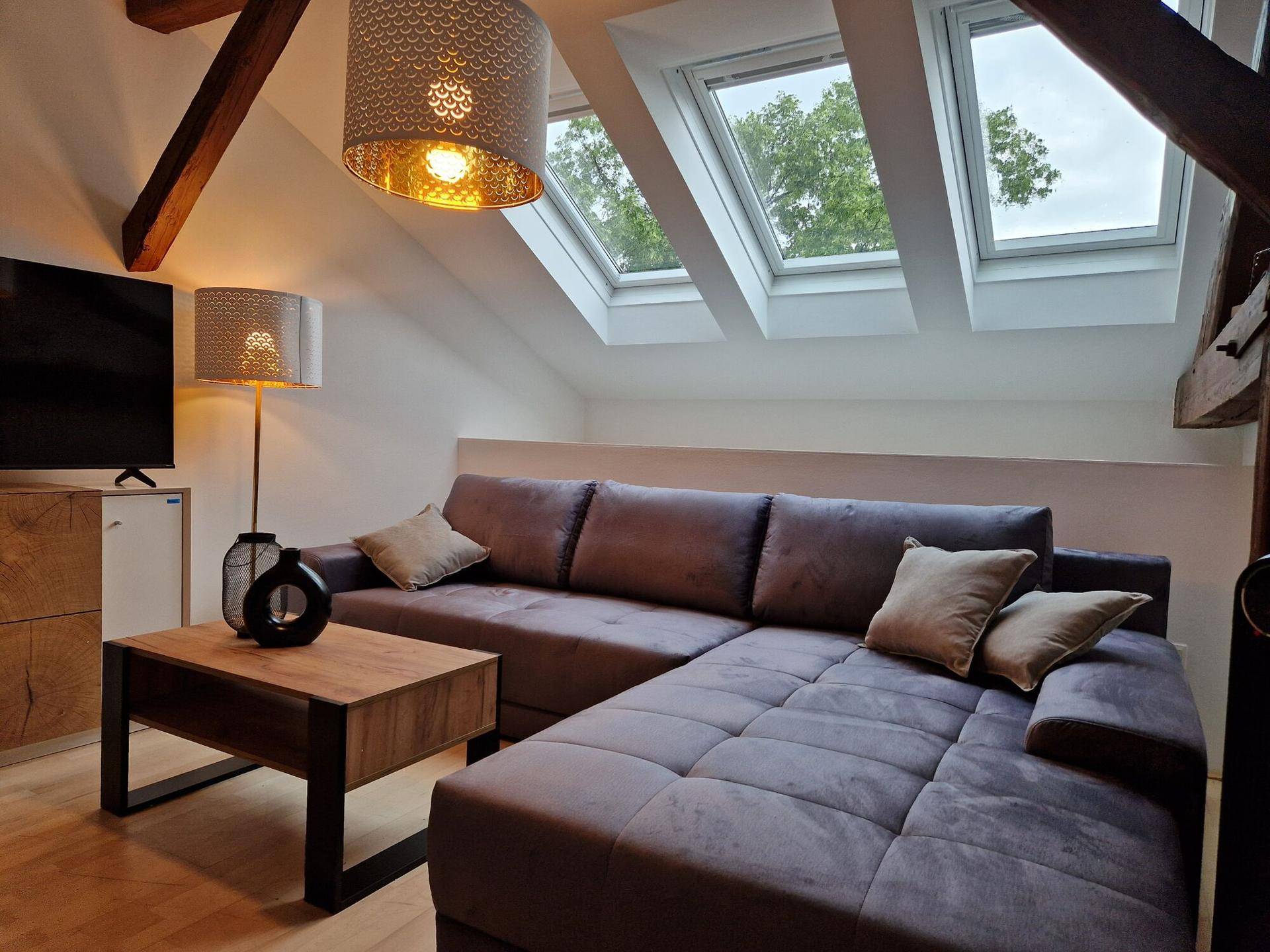 Detailansicht des Wohnzimmers mit Sofa, Couchtisch und Dachfenstern.