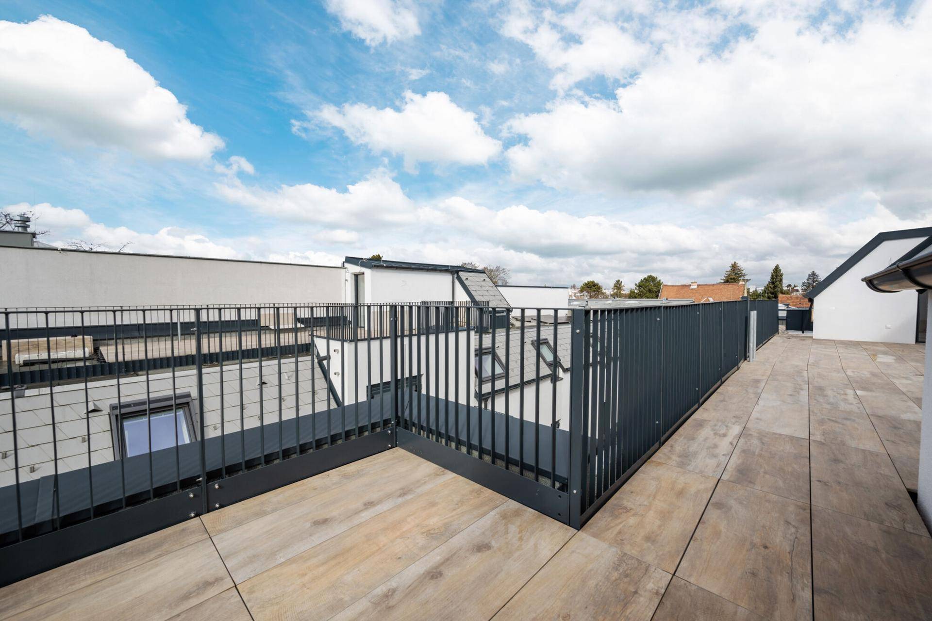 Weitläufige Dachterrasse mit modernem Metallgeländer und Blick über die Dächer.