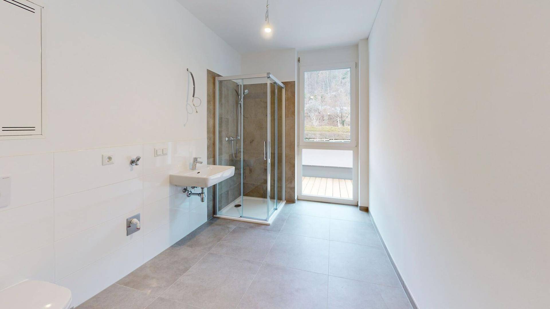 Modernes Badezimmer mit Duschkabine, Waschbecken und Fenster mit Blick ins Grüne.