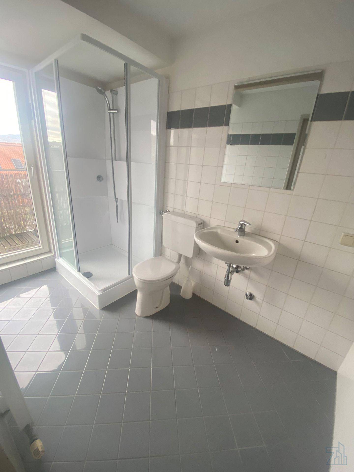 Helles Badezimmer mit Duschkabine, Toilette, Waschbecken und Fenster, bietet Tageslicht und Belüftung.