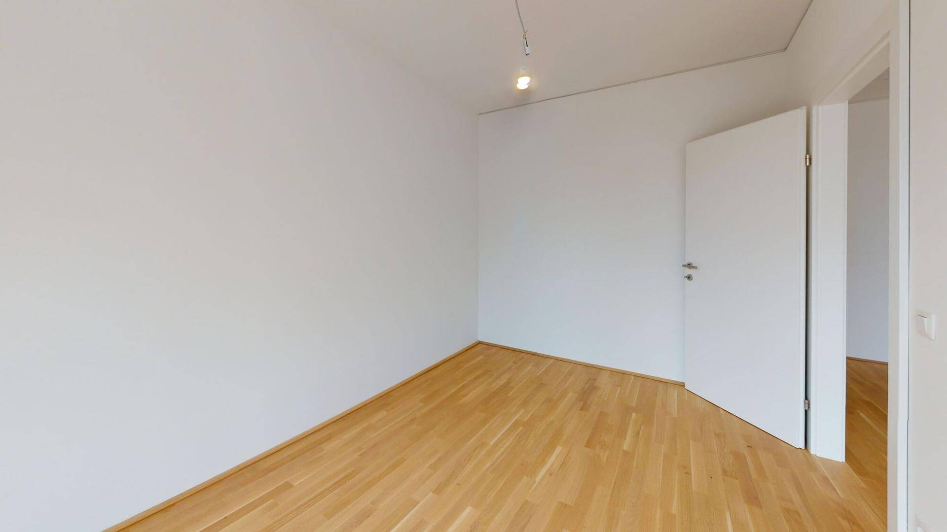 Helles Schlafzimmer mit Parkettboden und weiß gestrichenen Wänden, bereit zum Einzug.